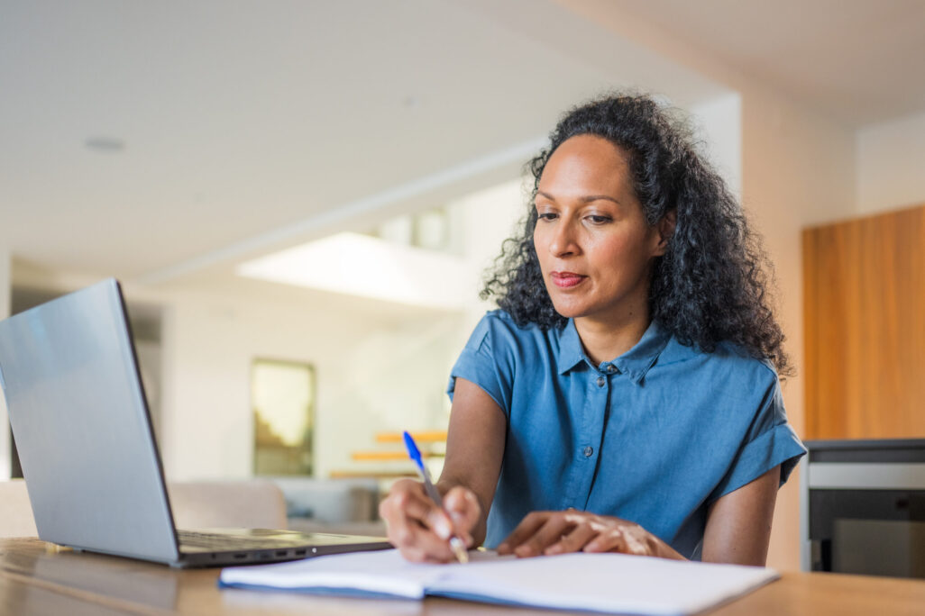 Woman studying online and taking notes